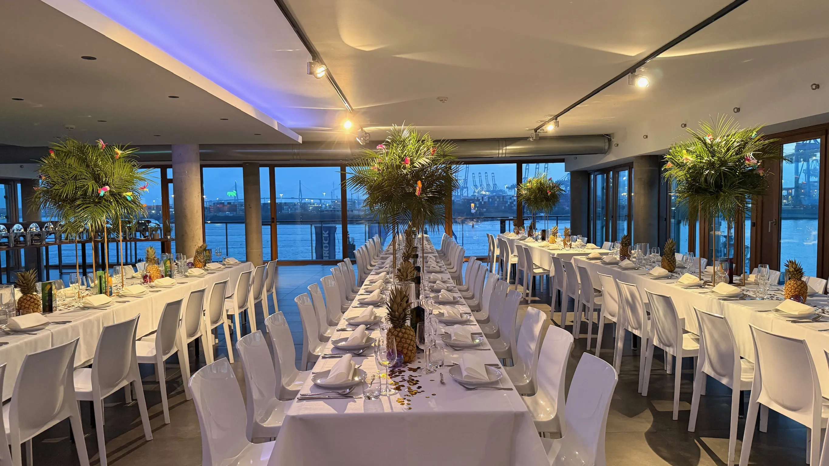 Festsaal am Abend, draußen leuchtet der Hafen